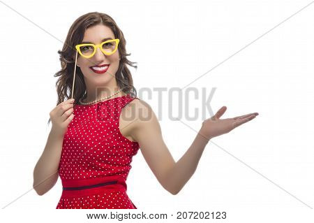 Portrait of Alluring Caucasian Female Holding Yellow Artistic Spectacles Near Eyes. Posing In Red Polka Dot Dress Against Pure White.Holding Hand in Front. Horizontal Image