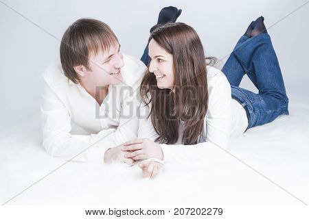 Young Family Lifestyle Ideas. Smiling and Laughing Caucasian Couple Having Time Together. Communicating on Floor And Looking Into Eyes of Each Other While Holding Hands In Touch. Horizontal Image