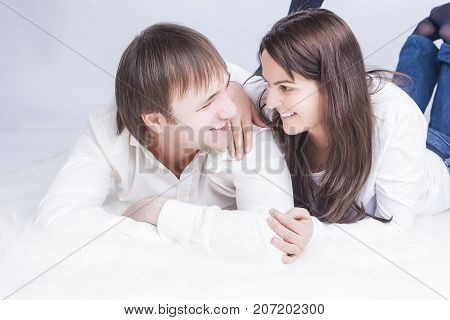 Family Ideas. Portrait of Happy Smiling Caucasian Couple Laying Together. Embracing and Looking into Each Other Eyes with .Holding Hands In Touch. Horizontal Image Composition