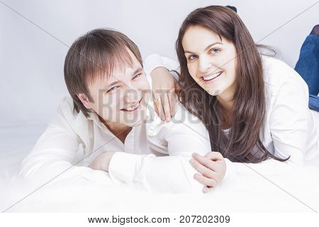 Family Ideas. Portrait of Happy Laughing Caucasian Couple Laying Together. Embracing and Looking into Each Other Eyes with .Holding Hands In Touch. Horizontal Image