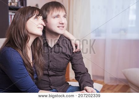 Family Ideas. Loving and Tender Young Caucasian Couple Sitting Together Embraced. Looking Upwards.Horizontal Image