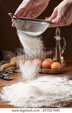 Sifting flour with flour filter. Making cookies A chef making cookies. The first step in cooking dumplings. Mans hands sifting flour through a sieve for baking. Chef's Hands Sifting Flour