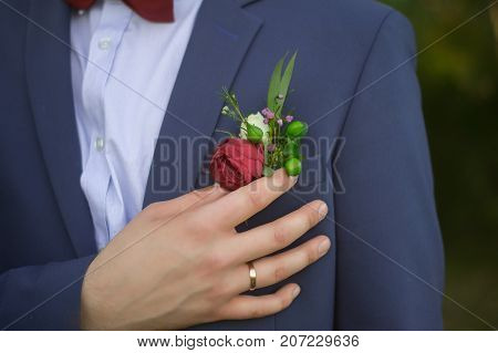 Handsome Groom In Blue Suit And Burgundy Bow Tie Adjusting Red Rose In Buttonhole Horizontal Photogr