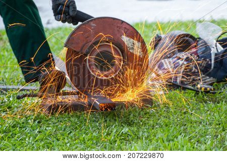Manual worker cutting steel machine is cutting steel pipe with sparks light for metal industrial element