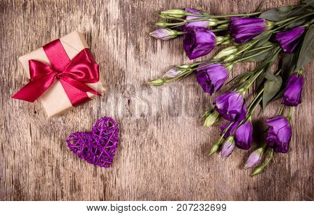Gift box with bow and purple flowers. Eustoma. Wicker heart. St. Valentine's Day