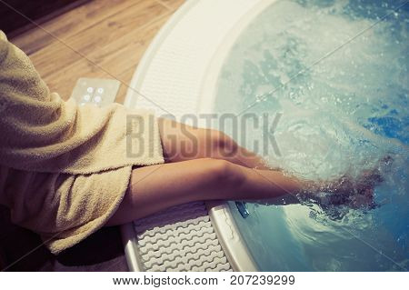 Woman with beautiful legs entering hot tub in spa resost
