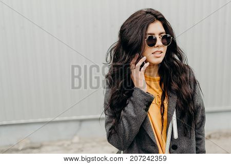 Portrait Of Stylish Modern Young Curly Woman In Coat Sunglasses. Phone Talking.