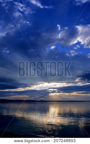 Sun Over The Lake Shines Through The Gray Clouds