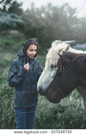 Travel to Iceland. a woman stroking a horse in the field