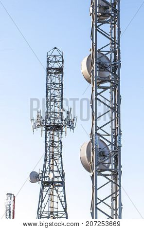 Broadcast relay station antennas at rising. Telecommunications towers with blue clear sky.