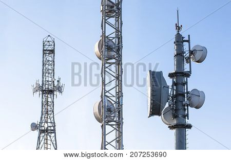 Broadcast relay station antennas at rising. Telecommunications towers with blue clear sky.