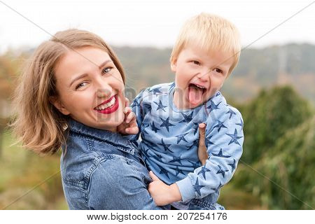 Happy joyful mother having fun throws up in the air child in autumn park