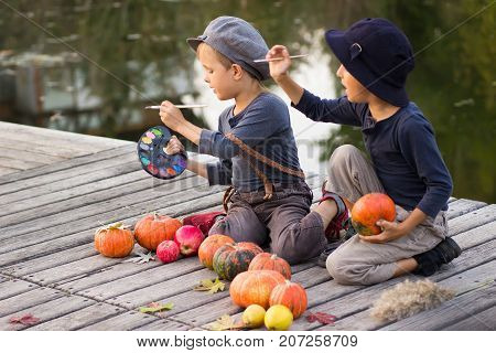 Nice children paint small Halloween pumpkins on the river bank