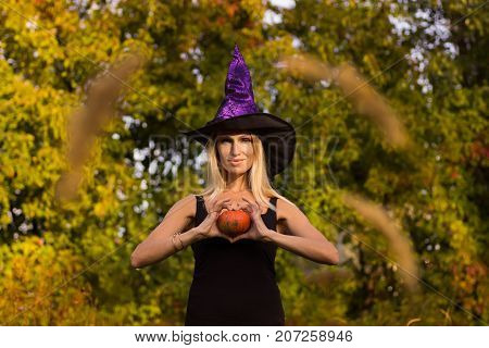 Nice girl in Halloween costume practicing yoga positions with pumpkins in her hands