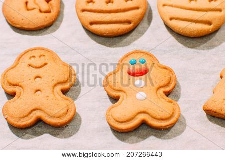 Homemade Christmas bakery top view. Festive background of gingerbread men on cooking sheet, close up. Family celebration and New Year traditions concept
