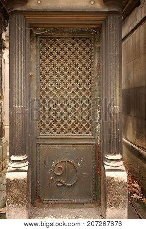 Paris France - November 5 2012: Entrance to an old tomb crypt at a cemetery. Pere Lachaise - world's most visited cemetery attracting hundreds of thousands of visitors annually to graves of those who have enhanced French life over past 200 years.