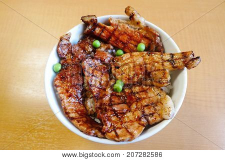 Top view Butadon bowl of rice topped with sliced pork and sweet sauceon wooden background. Popular japanese menu in 24 hours restaurant in Japan.