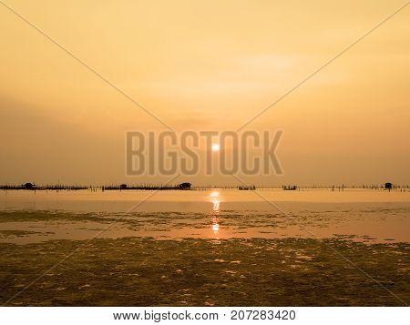 Beautiful sunset landscape orange golden sky above sea with silhouette of fish farms at sunset at Kohyo Songkhla Thailand.