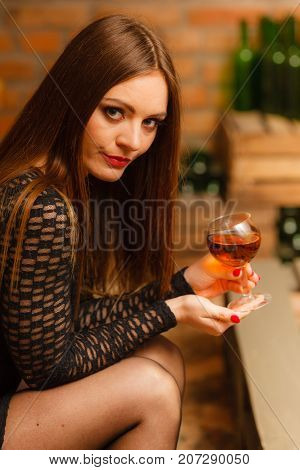 Elegant beauty lady long hair full make up wearing black dress tasting wine in rural cottage interior celler