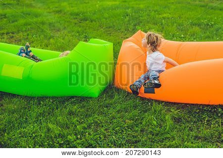 Two Cute Boys Resting On An Air Sofa In The Park.