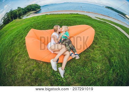 Mother and son resting on an air sofa in the park.. lamzac