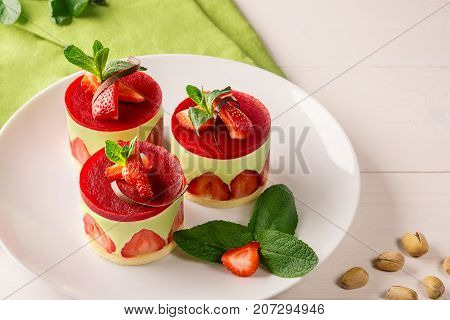 Dessert - sweet cake with strawberry on a plate with fresh mint and pistachios. Still life