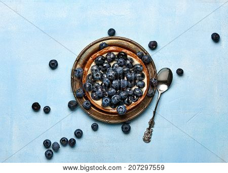 Blueberry tart, pie, tartlet with custard on blue stone background.