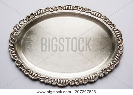 Stock photo of empty or blank silverware or oval shape plate with decorative border, isolated over white background, selective focus