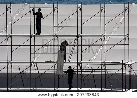 Silhouettes of workers on iron aluminum scaffold