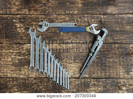 Set of combination wrenches and old adjustable wrenches on an old wooden boards background