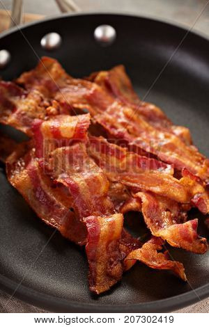 Cooked sizzling hot tasty crispy bacon on a skillet ready for breakfast