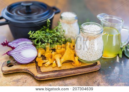 Ingredients for preparing risotto, Italian food. Fresh chanterelle mushrooms with arborio and herbs.