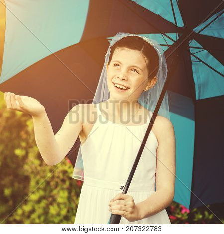 Young girl in communion dress under an umbrella