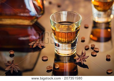 Cognac or liqueur coffee beans and spices on a glass table. Seasonal holidays concept.