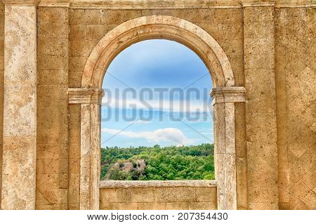 Italian view through the arch window, Tuscany, Italy. Medieval wall with arch window in Italy