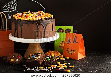 Halloween chocolate cake with candy corn and sprinkles on top and other holiday treats, copy space left for text