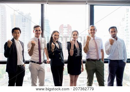 Portrait of happy business partners looking at camera with smiles and geture of teamwork.