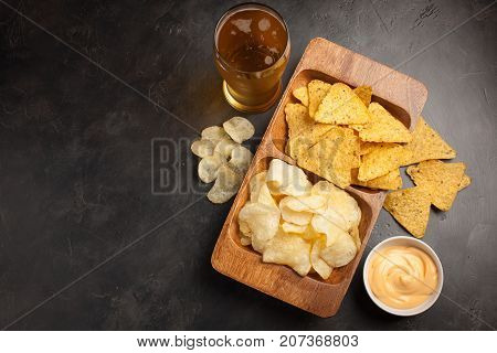Beer In Glasses Closeup On The Concrete Table. Beer And Snacks Are Chips And Nachos In Wooden Bowl W