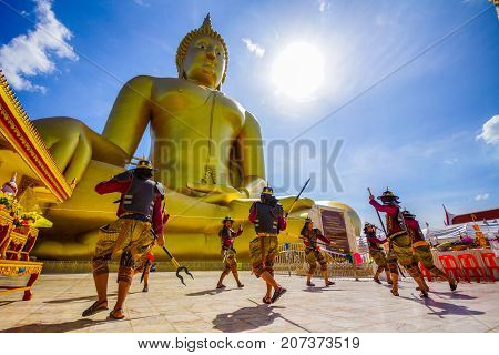 Angthong Thailand - July 15 2014: Actors performing fighting in ancient warrior style in front of large golden Buddha Image to celebrate Buddhist event at Wat Muang Buddhist temple in Angthong Thailand