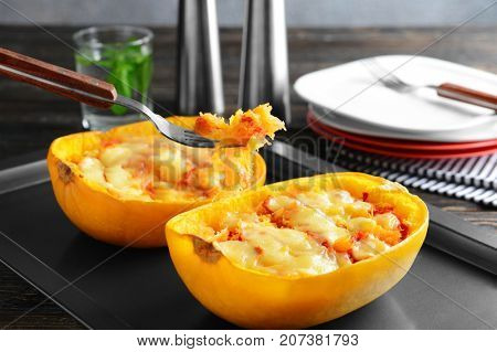 Fork with baked flesh and halves of stuffed spaghetti squash on baking sheet