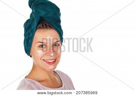 Happy female with facial moisturizer and bathtowel smiling at the camera on isolated background