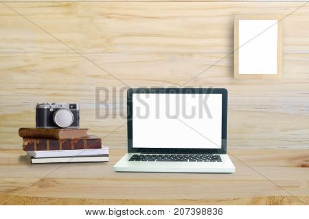 Laptop computer office supplies vintage book and camera on office wood table and blank photo frame on wood wall at home or studio. Mock up.