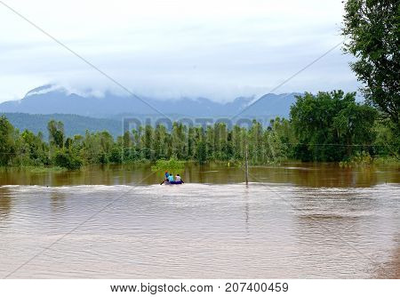 Phitsanulok Thailand- September 162017: Flash flood by red turbid water flows down from the mountain due to torrential rain with people paddling boats.