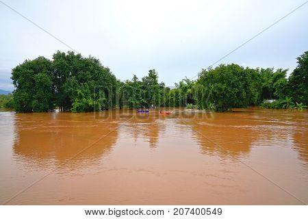 Phitsanulok Thailand- September 162017: Flash flood by red turbid water flows down from the mountain due to torrential rain with people paddling boats.