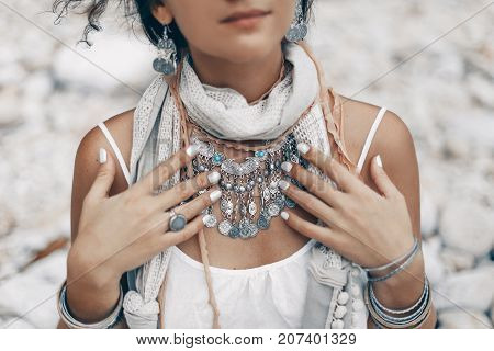 close up of boho styled woman on tropical beach with white pebble