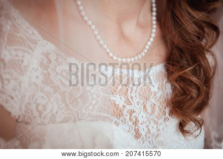 beautiful guipure on a dress of the bride. Pearl necklace on. Close up shot