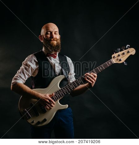 adult bearded man enthusiastically playing guitar on a black background