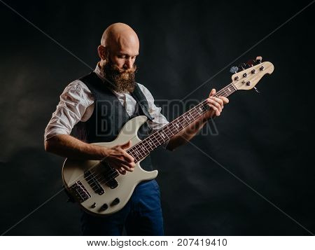 adult bearded man enthusiastically playing guitar on a black background