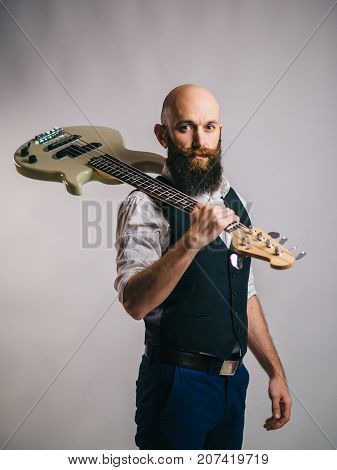 bearded man holding a guitar on his shoulder and looking at the camera