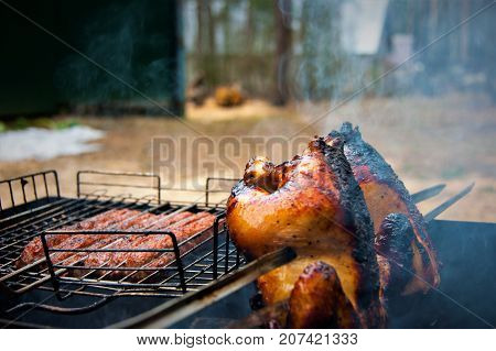 Grilled chicken and sausages on the fire with smoke